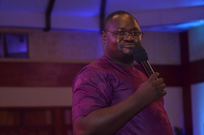 Dania Ebongue smiling in a red plaid shirt and tortoise shell glasses